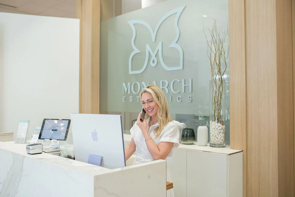 Receptionist at Monarch Esthetics in Charleston, SC warmly assisting a client over the phone.